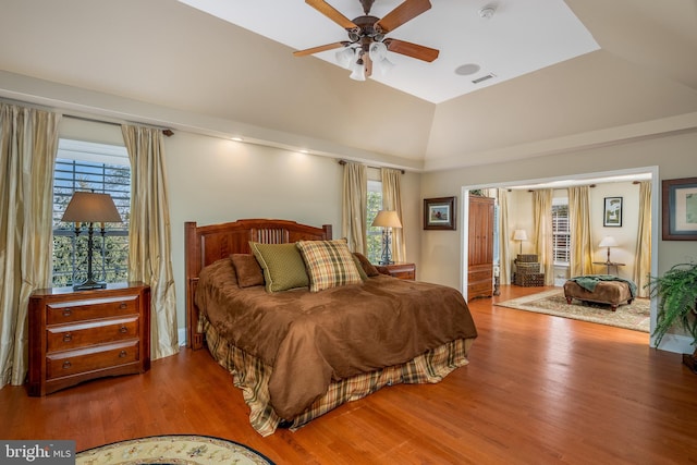 bedroom featuring ceiling fan, hardwood / wood-style flooring, vaulted ceiling, and multiple windows