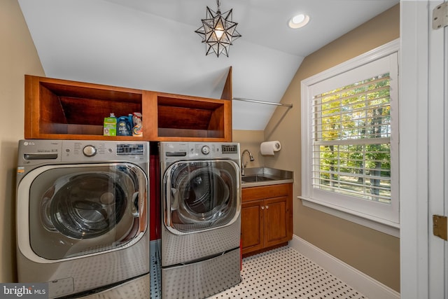 clothes washing area featuring sink, washing machine and dryer, and cabinets