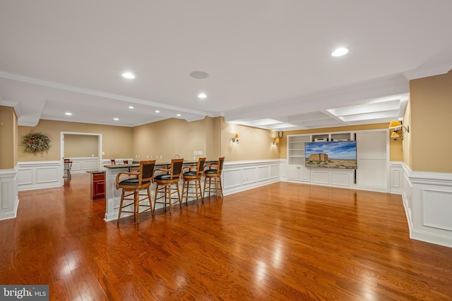 dining space featuring bar, wood-type flooring, and crown molding