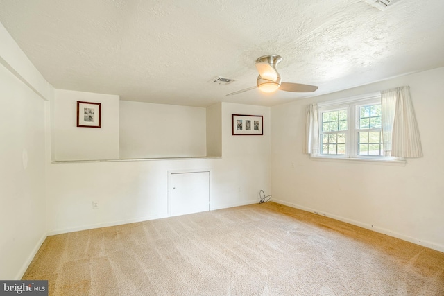 carpeted spare room with ceiling fan and a textured ceiling