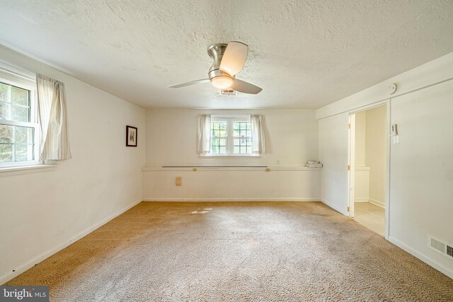 empty room featuring light carpet, a textured ceiling, and ceiling fan