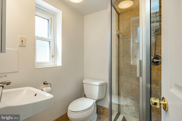 bathroom featuring toilet, sink, and a shower with shower door