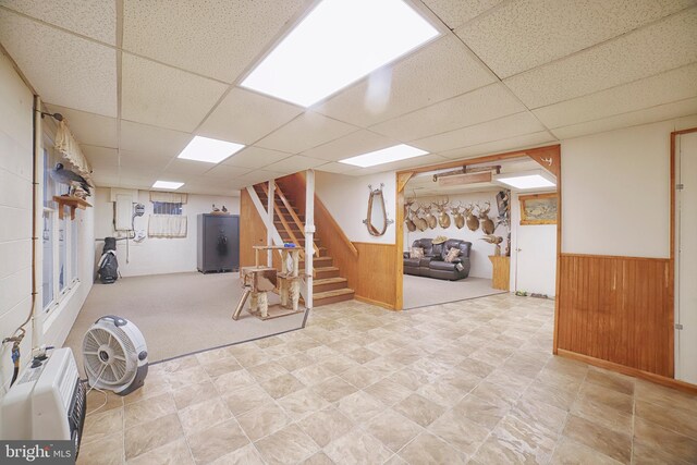 basement featuring a drop ceiling and wooden walls