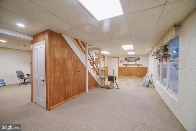 basement with a paneled ceiling and wood walls