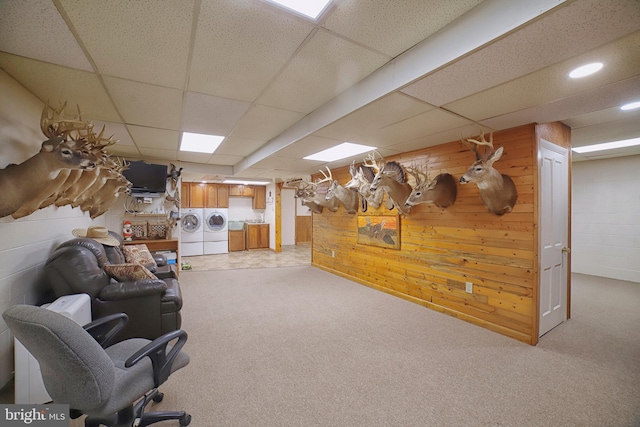 living room featuring a drop ceiling, wooden walls, and independent washer and dryer