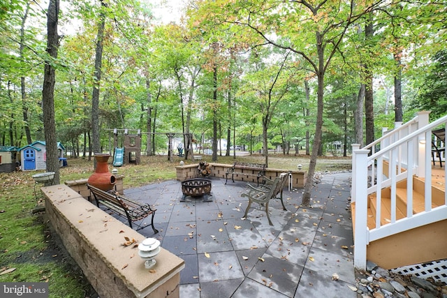 view of patio with a storage unit and an outdoor fire pit