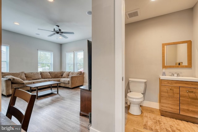 interior space with hardwood / wood-style floors, vanity, toilet, and ceiling fan