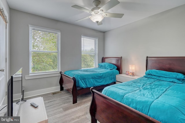 bedroom with multiple windows, light hardwood / wood-style floors, and ceiling fan