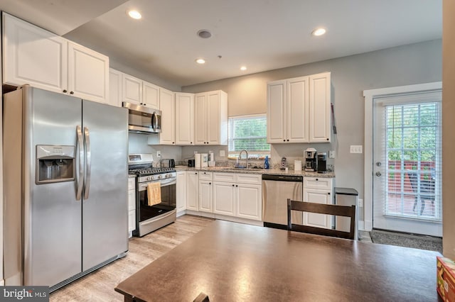 kitchen with white cabinetry, light stone countertops, stainless steel appliances, and plenty of natural light