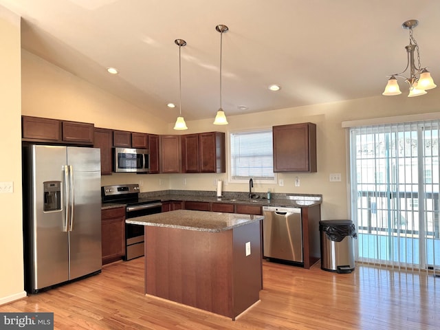 kitchen with a kitchen island, vaulted ceiling, hanging light fixtures, and appliances with stainless steel finishes