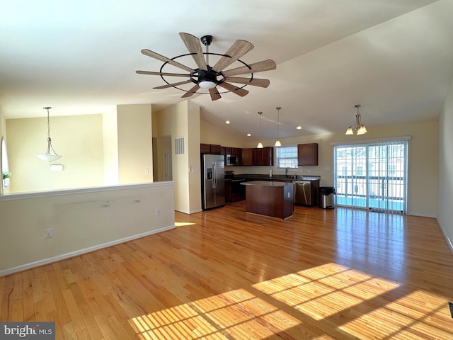 kitchen with stainless steel appliances, a kitchen island, pendant lighting, and vaulted ceiling