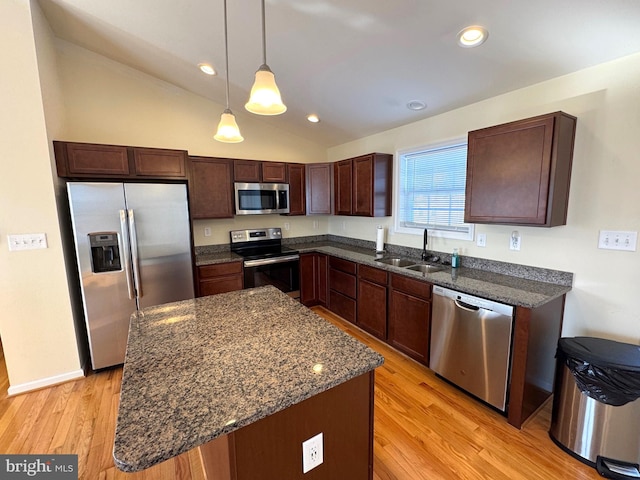 kitchen with appliances with stainless steel finishes, sink, decorative light fixtures, a center island, and light hardwood / wood-style floors