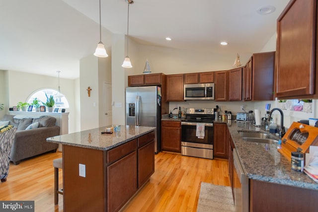 kitchen featuring appliances with stainless steel finishes, a center island, decorative light fixtures, sink, and a kitchen breakfast bar