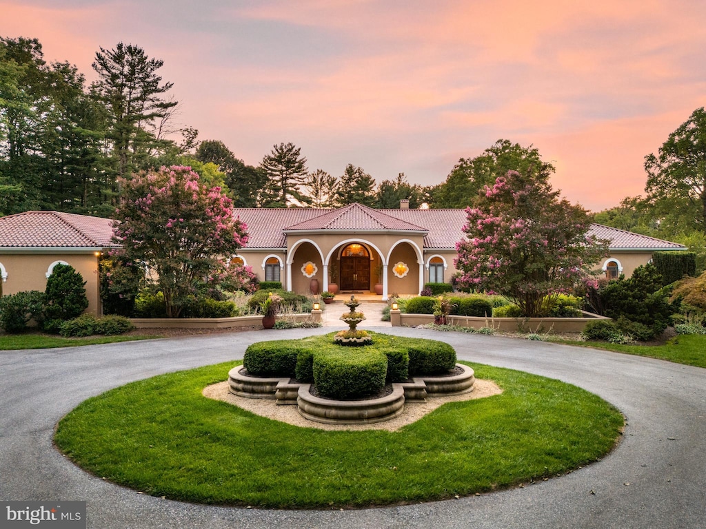 1100 Ginkgo Ln, Gladwyne, PA 19035 - mediterranean / spanish-style home featuring a chimney, stucco siding, curved driveway, and a tile roof