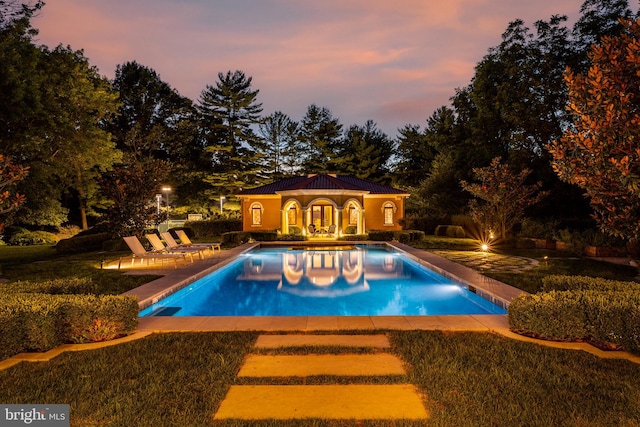 pool at dusk with a yard and a patio area