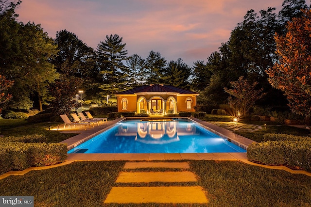 pool at dusk with a patio area