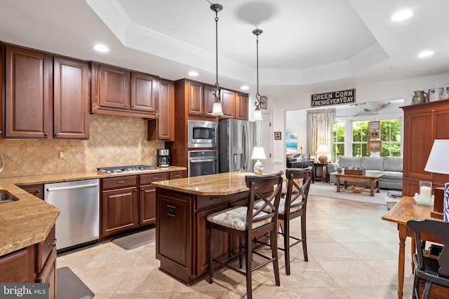 kitchen featuring pendant lighting, a kitchen island, a raised ceiling, appliances with stainless steel finishes, and crown molding