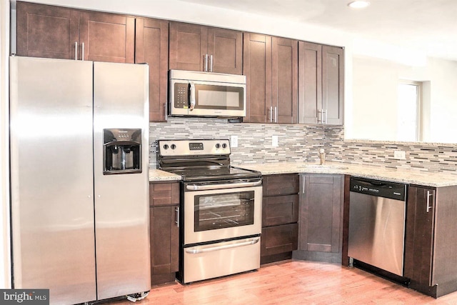 kitchen featuring backsplash, light wood-type flooring, appliances with stainless steel finishes, and dark brown cabinets