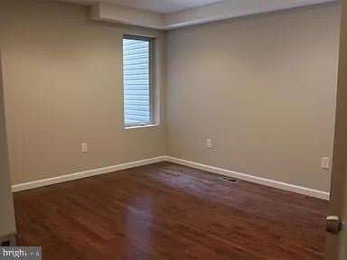 unfurnished room with baseboards and dark wood-style flooring