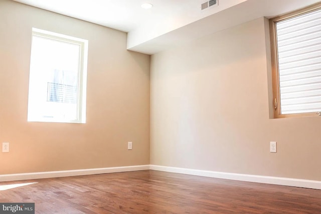 spare room featuring visible vents, baseboards, and wood finished floors