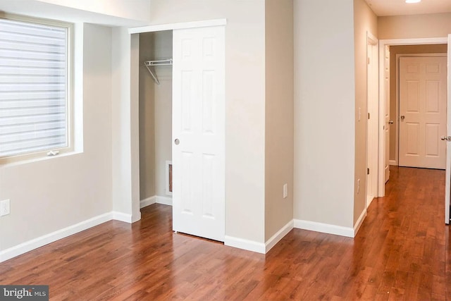 unfurnished bedroom with a closet, baseboards, and wood finished floors