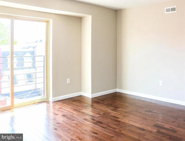 unfurnished room featuring visible vents, baseboards, and wood finished floors