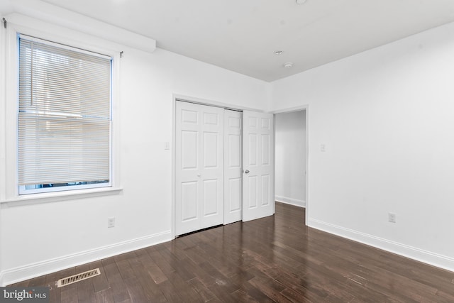 unfurnished bedroom featuring a closet and dark hardwood / wood-style flooring