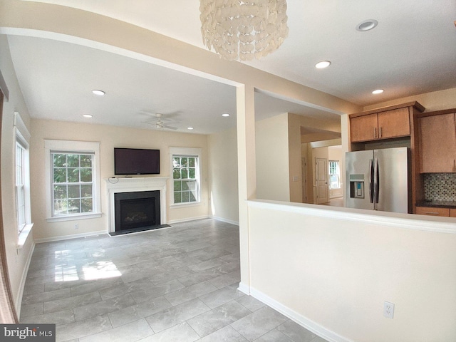 unfurnished living room with ceiling fan with notable chandelier