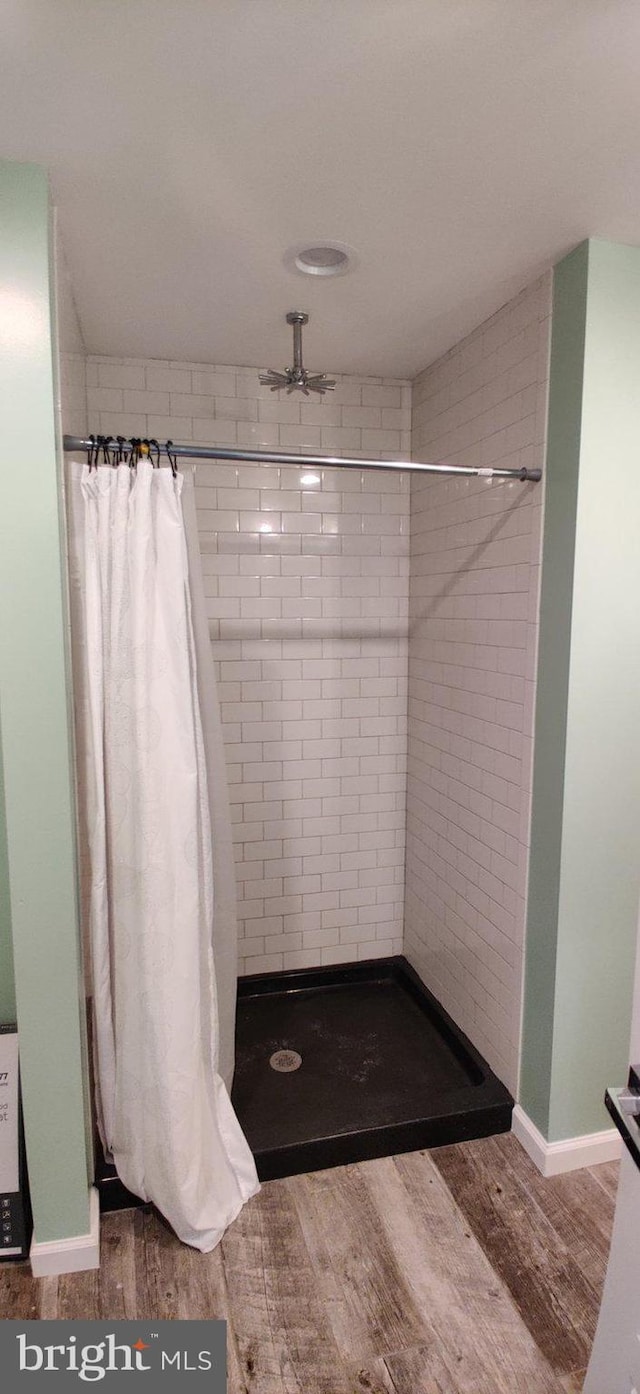 bathroom featuring ceiling fan, curtained shower, and wood-type flooring