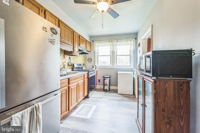 kitchen featuring stainless steel appliances, ceiling fan, light hardwood / wood-style floors, and sink