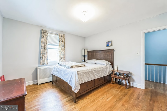 bedroom with radiator heating unit and light wood-type flooring