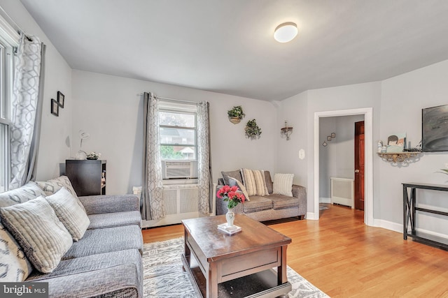 living room featuring hardwood / wood-style floors, cooling unit, and radiator heating unit