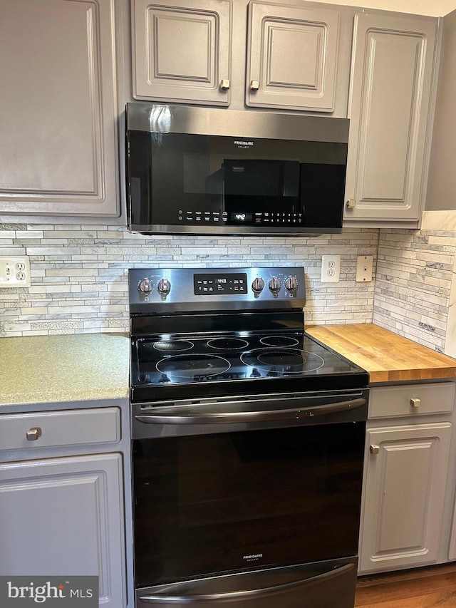 kitchen featuring hardwood / wood-style flooring, butcher block countertops, tasteful backsplash, and appliances with stainless steel finishes