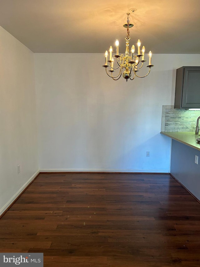 unfurnished dining area featuring dark hardwood / wood-style floors and an inviting chandelier