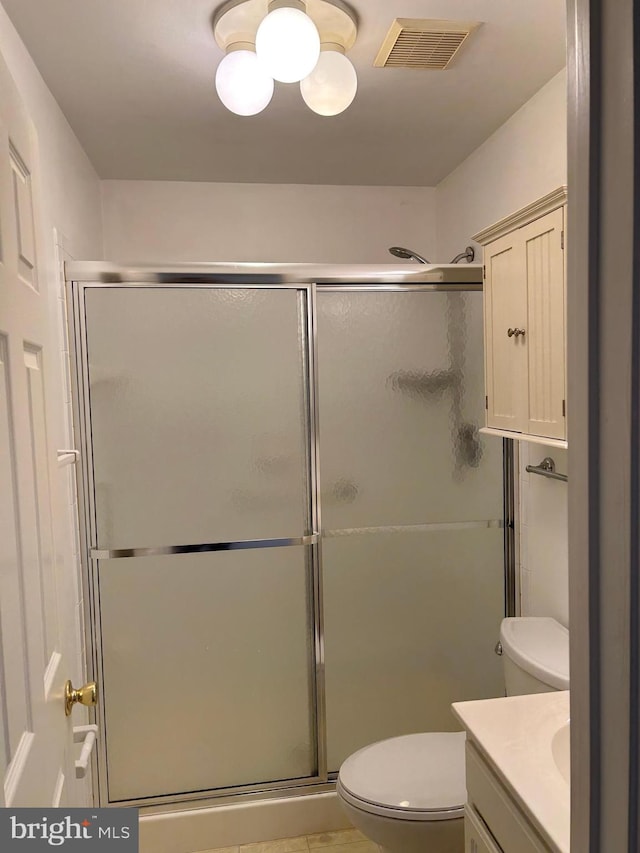 bathroom with vanity, toilet, and a shower with shower door