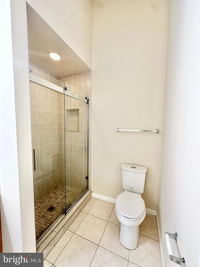 bathroom featuring tile patterned floors, a shower with shower door, and toilet