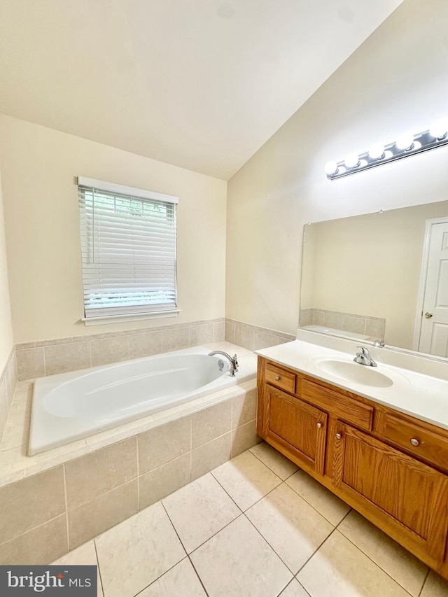 bathroom featuring vanity, a relaxing tiled tub, lofted ceiling, and tile patterned flooring