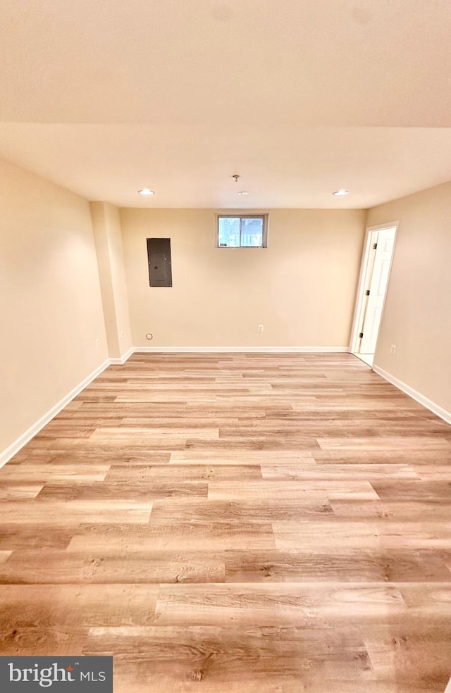 basement with electric panel and light hardwood / wood-style flooring