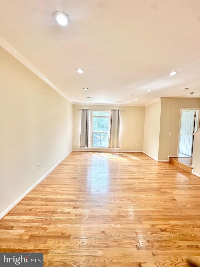 spare room featuring crown molding and light hardwood / wood-style flooring