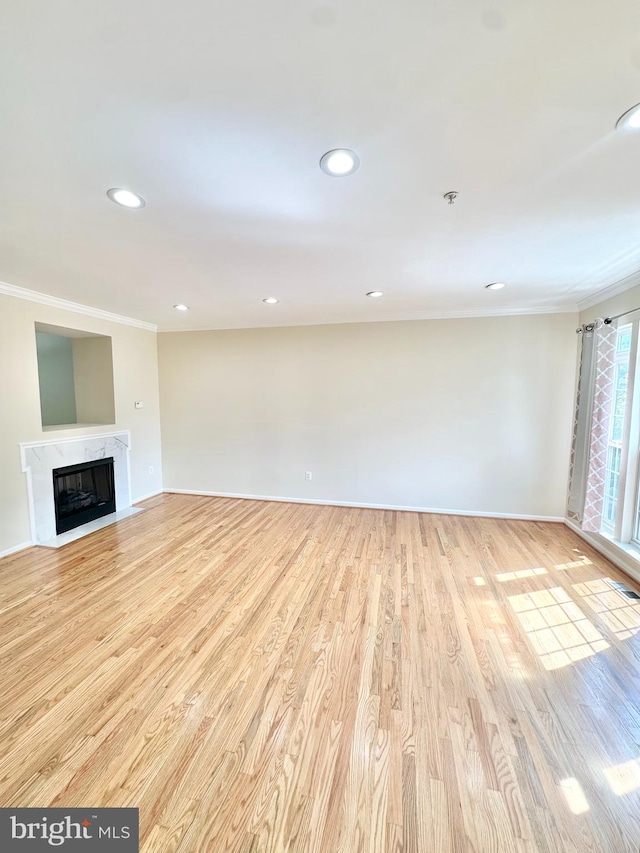 unfurnished living room with crown molding, light wood-type flooring, and a high end fireplace