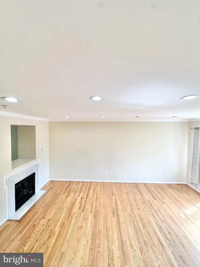 unfurnished living room with light hardwood / wood-style floors, crown molding, and a high end fireplace