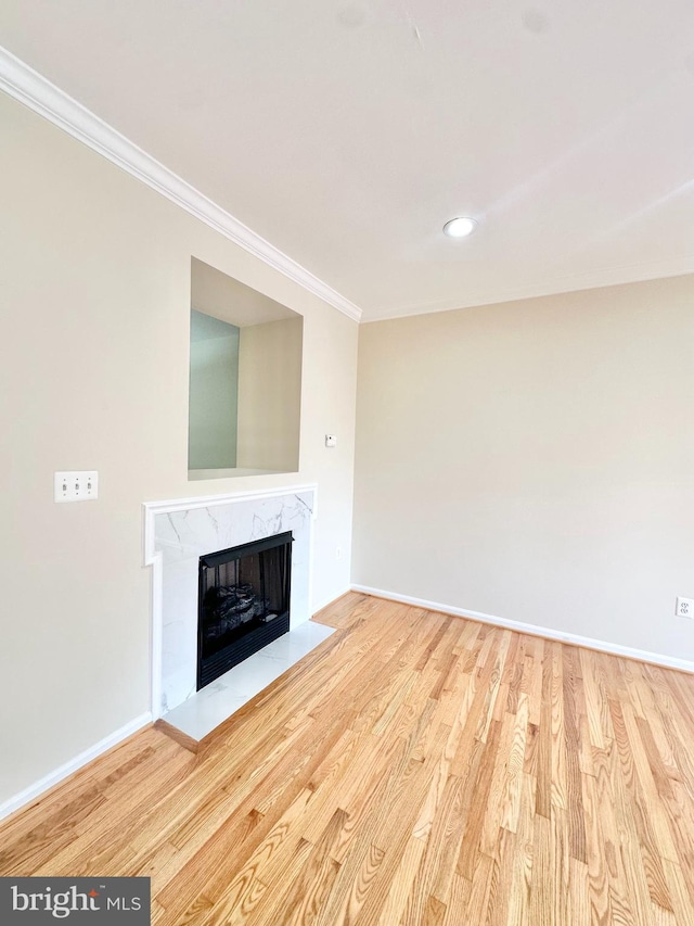 unfurnished living room featuring ornamental molding, a fireplace, and light wood-type flooring