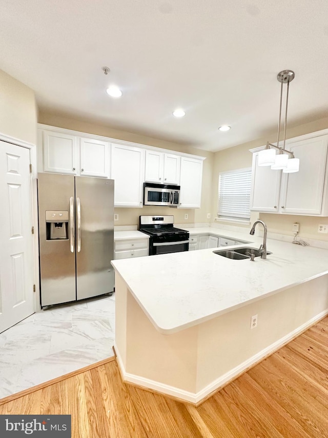 kitchen featuring decorative light fixtures, white cabinets, stainless steel appliances, and sink