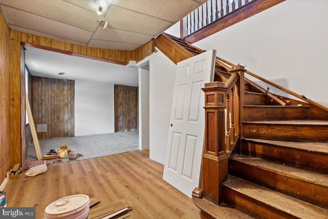 stairs with hardwood / wood-style floors and wooden walls