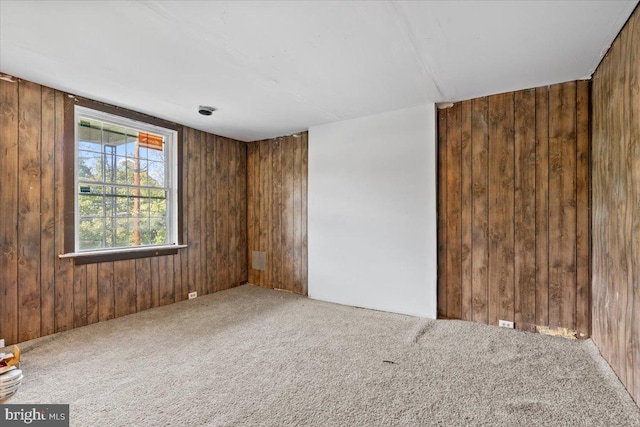 carpeted empty room featuring wooden walls