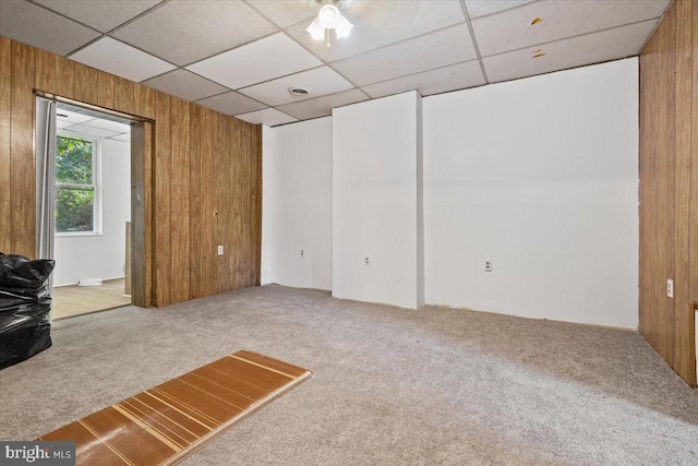 interior space featuring a paneled ceiling and wooden walls