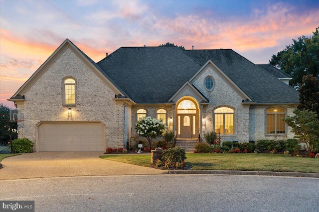 french country home featuring a garage and a yard