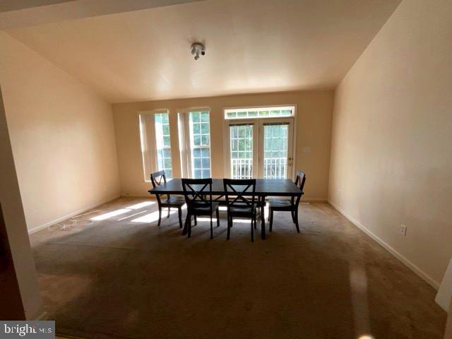 carpeted dining space with vaulted ceiling