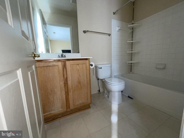 full bathroom with tiled shower / bath, vanity, toilet, and tile patterned floors