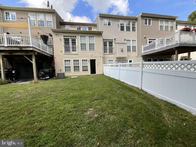 back of property with a yard, central AC, and a wooden deck